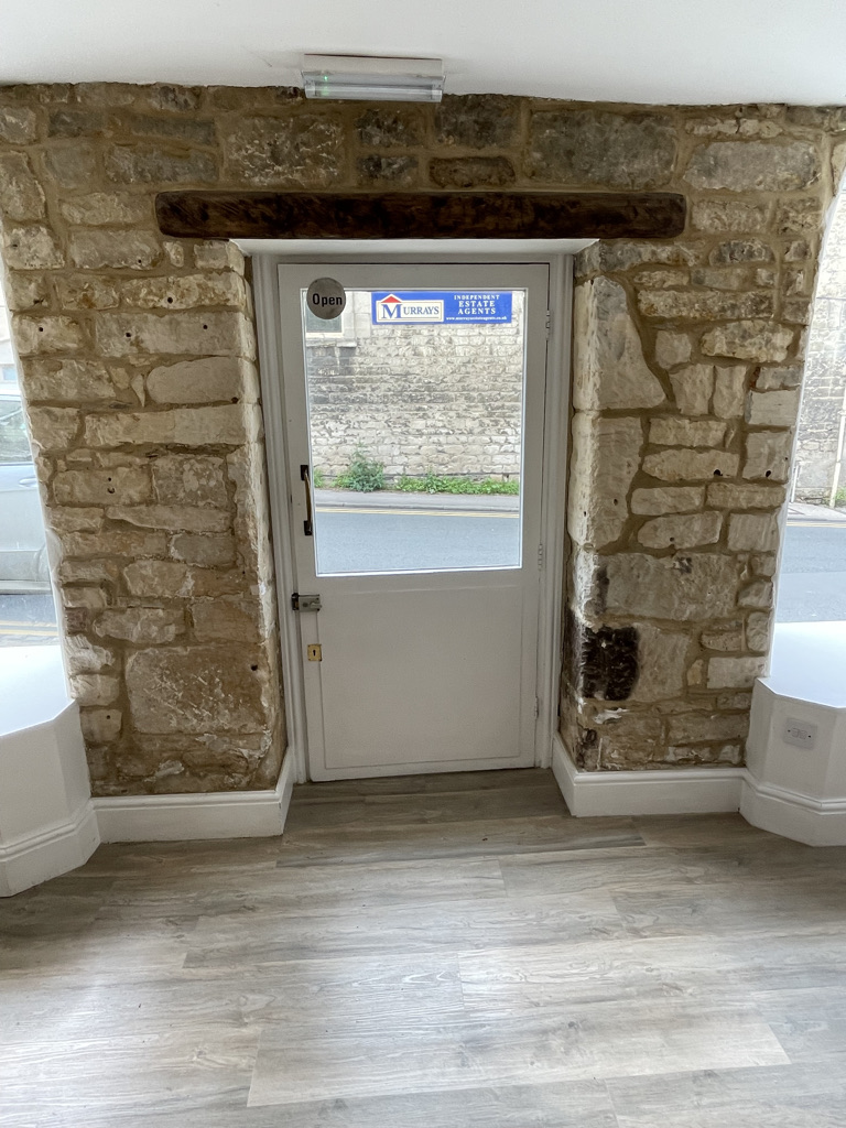 The image shows the interior of a store with a white door and a stone wall. The alt text for the image is: "Inside a store...
